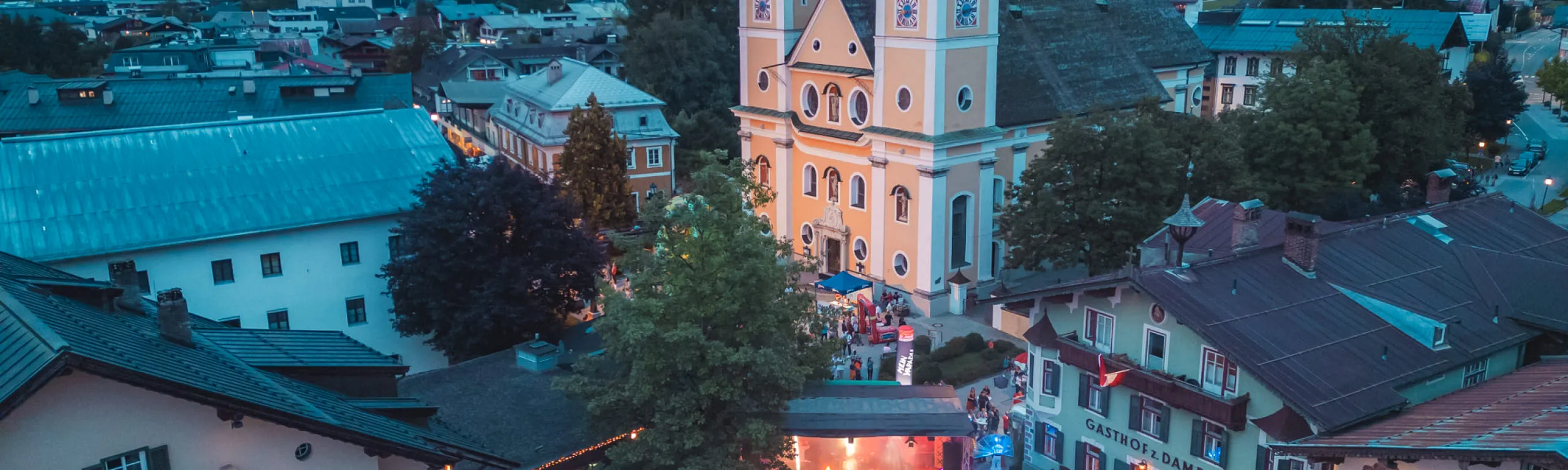Abendveranstaltung im Ortszentrum von St. Johann in Tirol mit Pfarrkirche und Bergpanorama