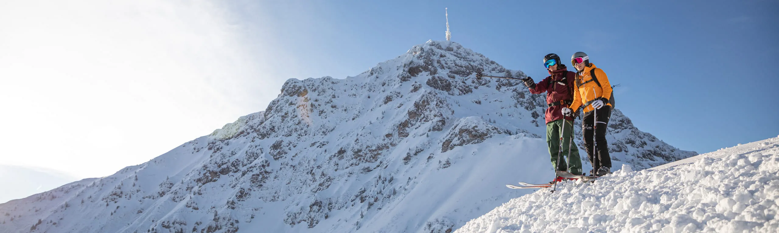 Zwei Wanderer auf einem verschneiten Gipfel bei Sonnenschein